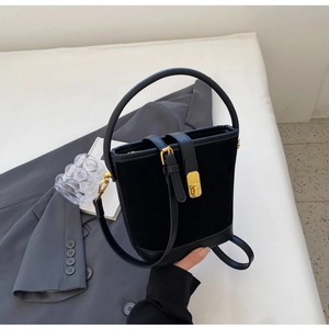 Close-up of black suede bucket bag with gold hardware and smooth leather details