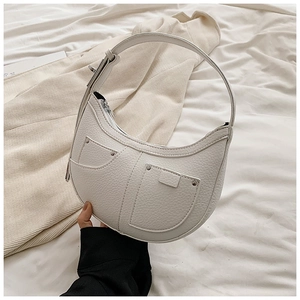 Close-up of white lychee texture crescent bag featuring dual front pockets and rivets