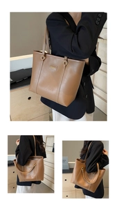 Detail of large brown tote bag showing contrast white stitching and minimalist brand logo