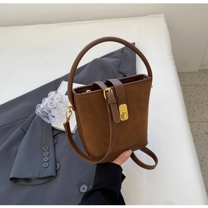 Detail of vintage brown suede bucket bag with gold hardware and stylish twist lock
