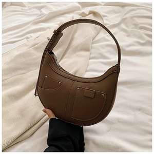 Detailed close-up of brown crescent bag showing litchi texture leather and silver hardware