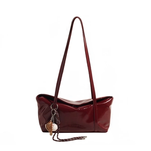 Glossy deep red underarm bag with baseball glove charm and minimalist straps