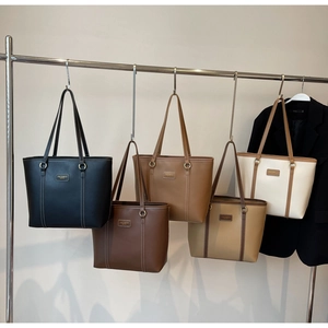 Detailed view of leather tote bags in five colors hanging on silver metal hangers