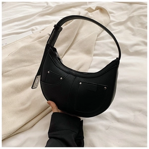 Close-up of black lychee grain leather crescent bag featuring silver rivet pocket details
