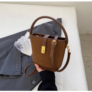 Detail of vintage brown suede and leather bucket bag with gold twist lock and sturdy handle