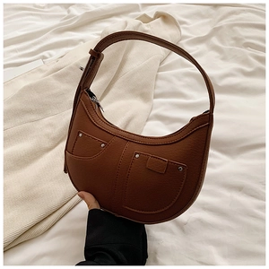 Detail of a brown PU leather crescent hobo bag with silver rivets and decorative stitching
