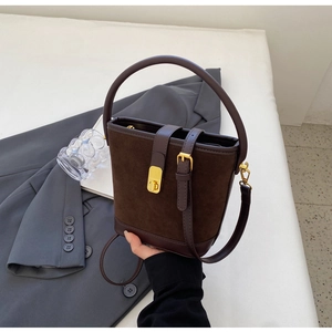 Detail of vintage brown suede bucket bag featuring a gold twist lock and dual strap design