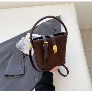 Detail of vintage dark brown suede bucket bag featuring leather trim and gold buckle