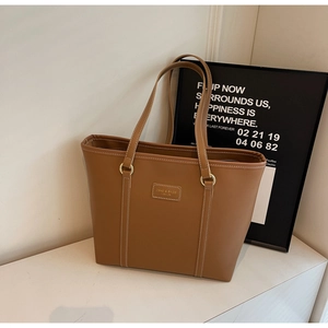 Detailed view of brown PU leather tote bag with white contrast stitching and logo