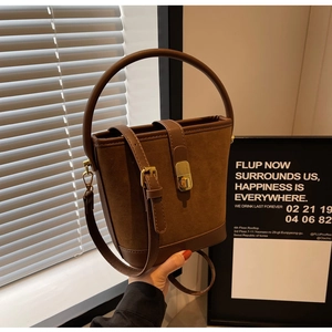 Détail du sac seau en daim marron avec poignée en cuir et fermoir métallique doré