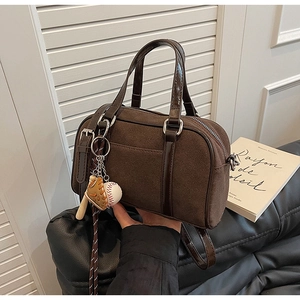 Détail d'un sac bowling marron givré avec pendentif baseball rétro et anses brillantes