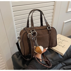Détail du sac bowling vintage marron chocolat avec texture suédée et breloque baseball