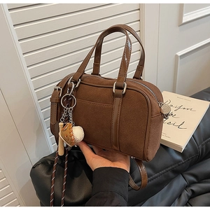 Détail du sac bowling vintage en daim marron avec breloques de baseball et bandoulière