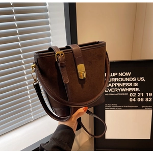 Gros plan d'un sac seau vintage en daim marron avec fermoir doré et détails en cuir