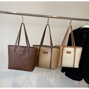 Detailed close-up of three tote bags in brown and khaki with metal rings and logo