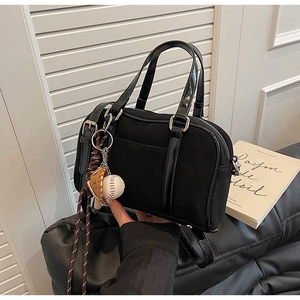 Gros plan du sac bowling noir mat sur canapé en cuir avec détail de breloque de baseball