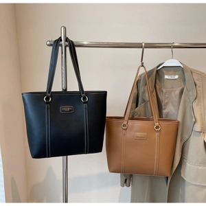 Close-up of black and brown leather tote bags with elegant white contrast stitching