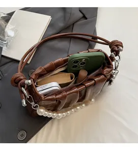 Detail showing internal storage of brown pleated baguette bag with pearl handle decoration