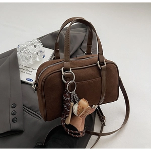 Détail du sac bowling rétro en daim marron avec pendentif baseball et longue poignée