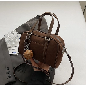Gros plan du sac bowling mat marron foncé avec poignées et pendentif boule décoratif