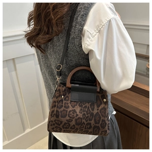 Detail of leopard print tote bag with wooden handle and gold rivet accents