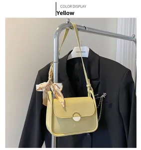 Detail of yellow leather crossbody bag with metal buckle and decorative printed silk scarf