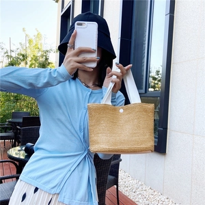 Minimalist woven straw tote bag with white fabric handles and magnetic closure