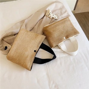 Detail of woven straw tote bags with contrasting black and white handles and button closures