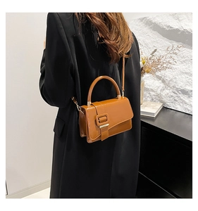 Detailed view of a caramel brown leather crossbody bag with a decorative square buckle
