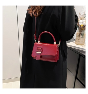 Deep red glossy square handbag worn with black coat for a stylish street look
