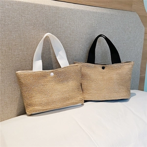 Detail of hand-woven straw handbags featuring circular buckles and webbing handles