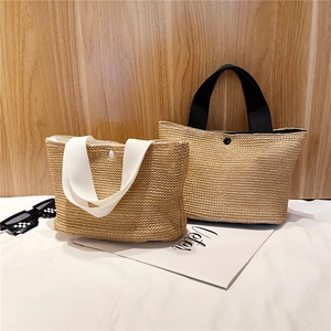 Detail of woven straw tote bags with canvas handles and snap closure for summer