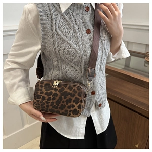 Chic leopard print crossbody bag with double gold zippers on a stylish model