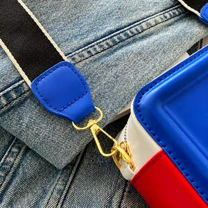 Détail du crochet doré et de la bandoulière tissée sur un sac à bandoulière tricolore