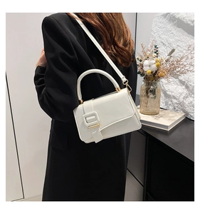 Detailed back view of a white minimalist square crossbody bag worn with a black blazer