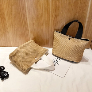 Detail of handwoven summer straw tote bag with snap button closure and fabric handle