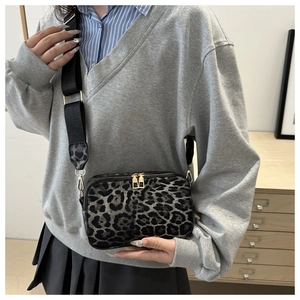 Detail view of the leopard print crossbody bag with golden double zippers and wide strap