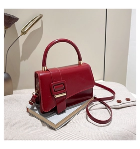 Detail of red patent leather handbag featuring large square buckle and gold hardware
