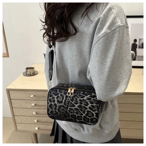 Fashionable leopard print crossbody bag with dual metal zippers and wide fabric strap
