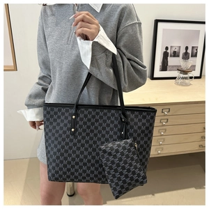 Detailed close-up of a large black tote bag with gray M letter prints and a matching pouch
