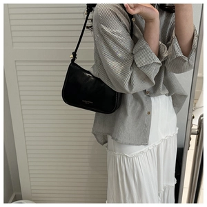 Détail d'un sac sous les aisselles noir demi-lune avec texte mode blanc et bandoulière fine