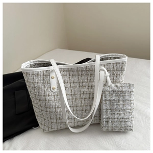 Gros plan d'un sac cabas en tweed blanc avec pochette assortie et détails en métal doré