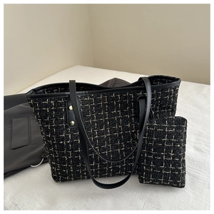 Détail d'un cabas en tweed noir et doré avec lanières en cuir et pochette assortie