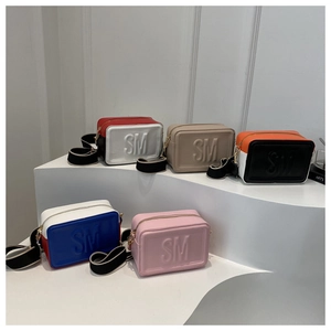 Plusieurs sacs bandoulière en cuir coloré avec larges sangles sur un support étagé