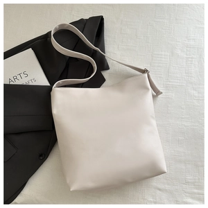 Close-up of beige tote bag made of smooth faux leather on white textured fabric background