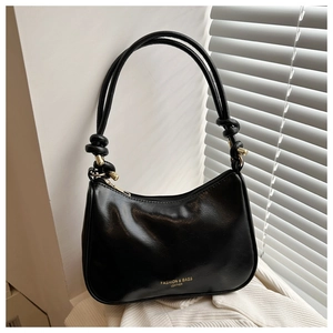 Détail du sac hobo en cuir brillant noir avec bandoulière nouée et dorures