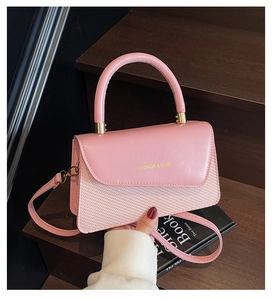 Detail view of pink synthetic leather and woven texture with gold lettering and strap