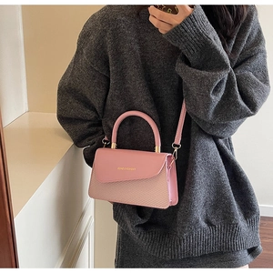 Pink crossbody bag with leather and woven texture shown on a model in casual attire