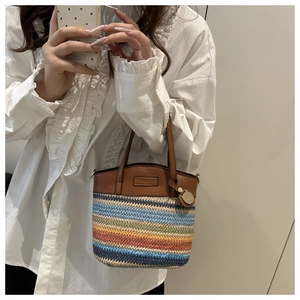 Detailed texture of colorful woven straw bucket bag with premium brown leather handle