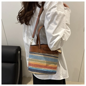 Detailed shot of rainbow straw bucket bag with brown leather handles and shoulder strap